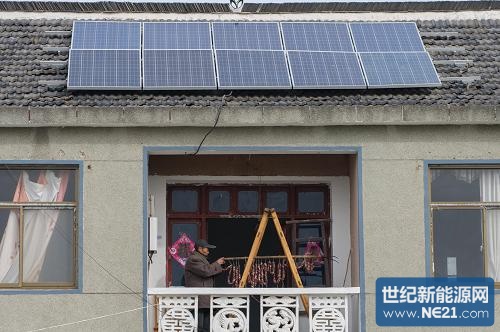 11月26日,安徽省合肥市肥东县长临河镇罗洪村村民王建春在阳台上晒香肠,屋顶是他家的家庭分布式光伏发电站太阳能板。新华社记者 杜宇 摄